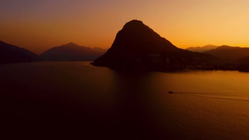 Boat Moving Across Mountain Lake at Dark Sunset Drone View