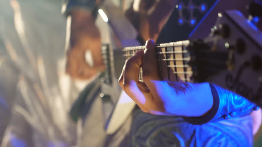 Unrecognizable man playing on electric guitar at stage during rock concert. Musician playing solo on guitar. Close up Slow motion