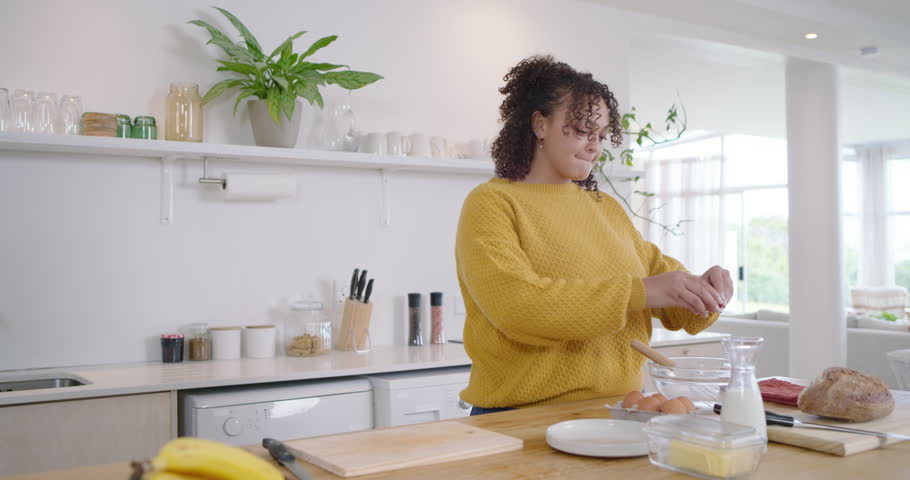 African-American couple starting breakfast, woman cracking eggs in bowl as man dicing veg on island. Kitchen, cooking, partnership, romance, sunlit, modern, morning