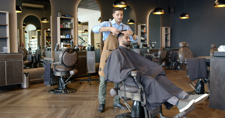 African American barber in apron cutting client