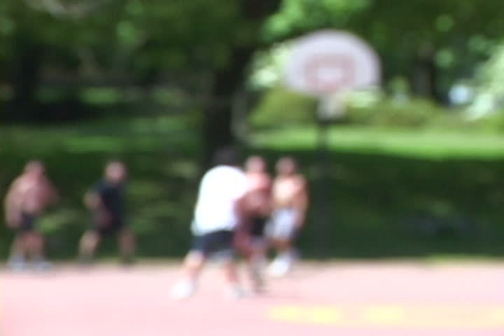 Group of men play basketball at park with soft focus for background. Great for