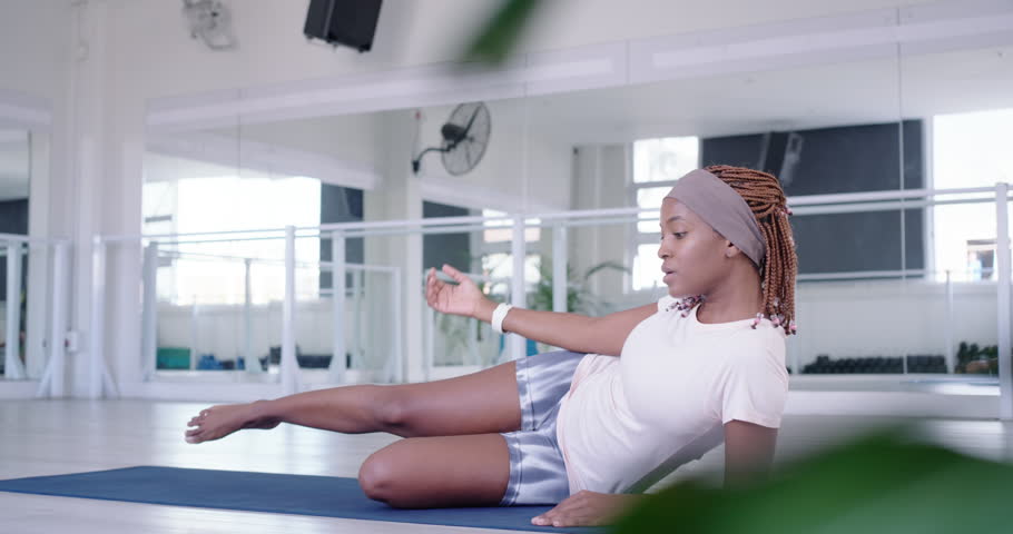 Adult African woman starting on studio mat doing leg lifts rolling up stretching for mobility. Sidelying, kneeling, fitness, workout, flexibility, balance, posture