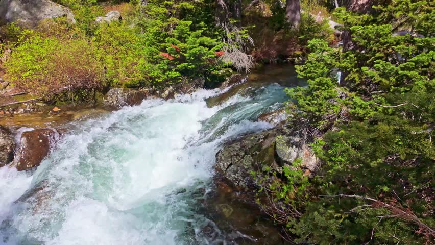 Cascade Creek waters flowing through rugged terrain beneath the Teton mountain range from Lake Solitude