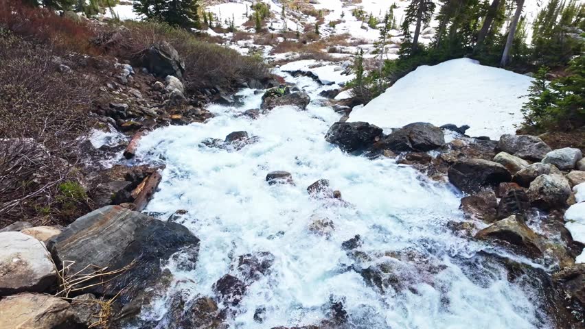 Sweeping panoramic view of the Teton mountain range with a snow covered trail leading to Solitude Lake
