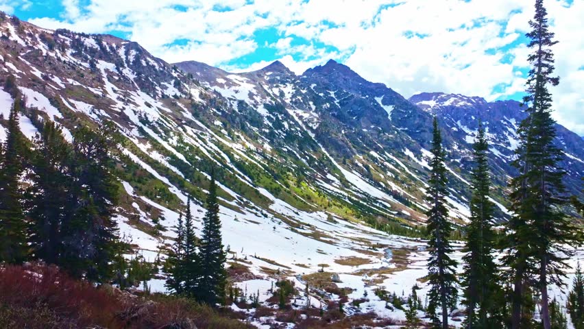 Sweeping panoramic view of the Teton mountain range with a snow covered trail leading to Solitude Lake
