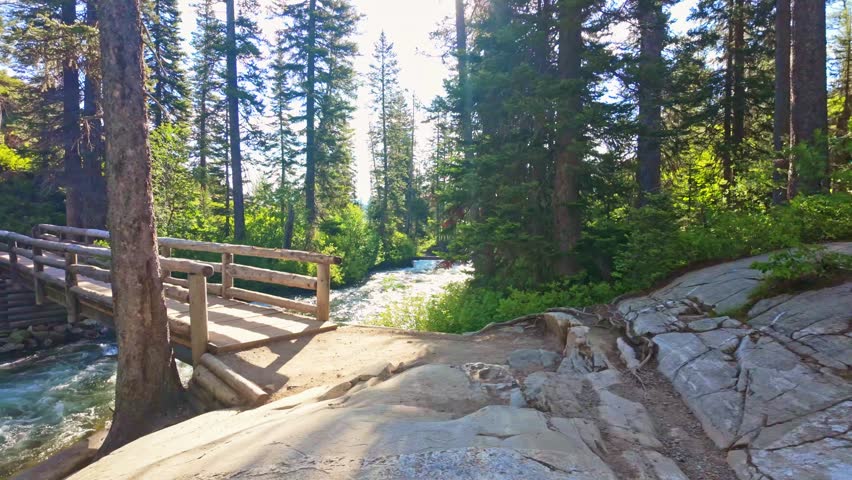 Cascade Creek flows beneath a rustic wooden bridge along the Hidden Falls Trail in Grand Teton