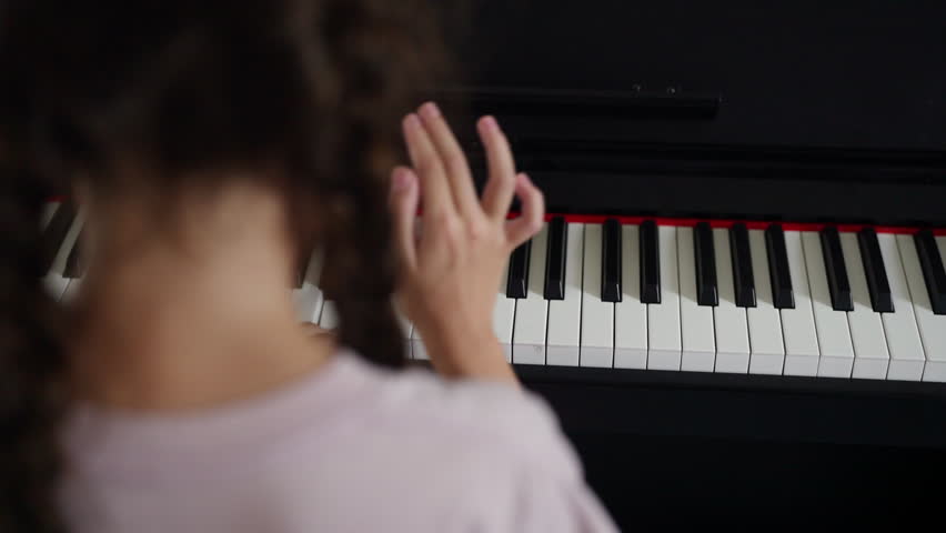 Young girl practicing piano in classroom developing music skills creativity concentration confidence through school music education performing arts training and childhood learning