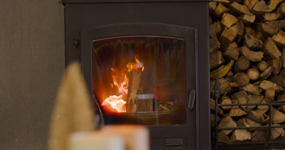Hot embers are igniting upright log inside wood stove, flames climbing, charring log, warming home. Fireplace, hearth, glow, cozy, ambience, rustic, warmth