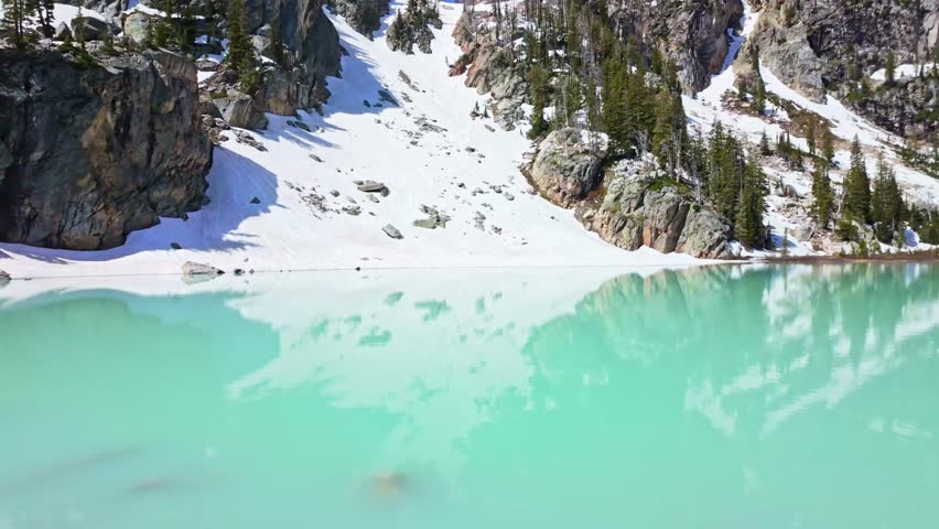 Panoramic view of turquoise Delta Lake beneath the snow capped peaks of Grand Teton National Park in Wyoming