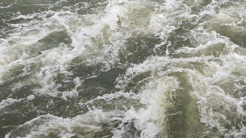 Static shot of rushing river white water rapids covered in heavy foam and splashing currents