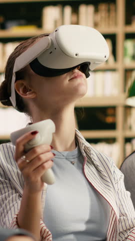 Portrait format: A student wears VR glasses and holds controllers in university library, framing virtual training, library technology and future education.