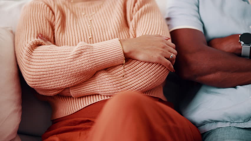 Conflict, sofa and couple with crossed arms for fight, divorce and tension for argument in home. Hands, marriage and man with woman with disagreement, frustrated and upset for relationship issue