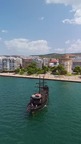 Aerial view of the White Tower landmark on the waterfront with pirate tour boats in Thessaloniki, Greece