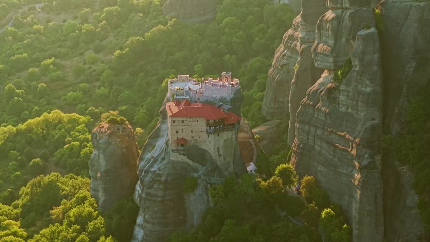 Aerial view of the Holy Monastery of Saint Nicholas Anapausas nestled on a rocky spire among the giant cliffs of Meteora at sunset, Greece