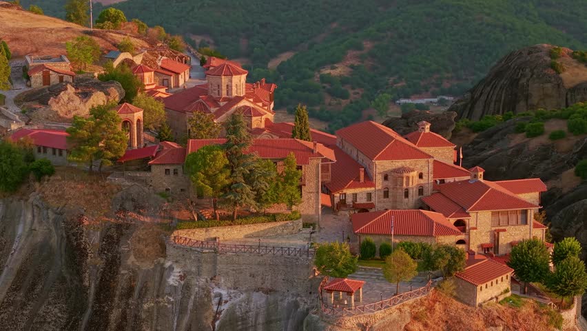 Aerial view of the Holy Monastery of Great Meteoron on a massive rock pillar during a misty sunrise in Meteora, Greece
