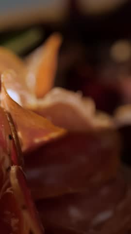 Meat appetizer. jamon. Delicious variety of meat appetizers, Prosciutto crudo or jamon meat with rosemary on serving wooden platter. The chef puts jamon on serving board.