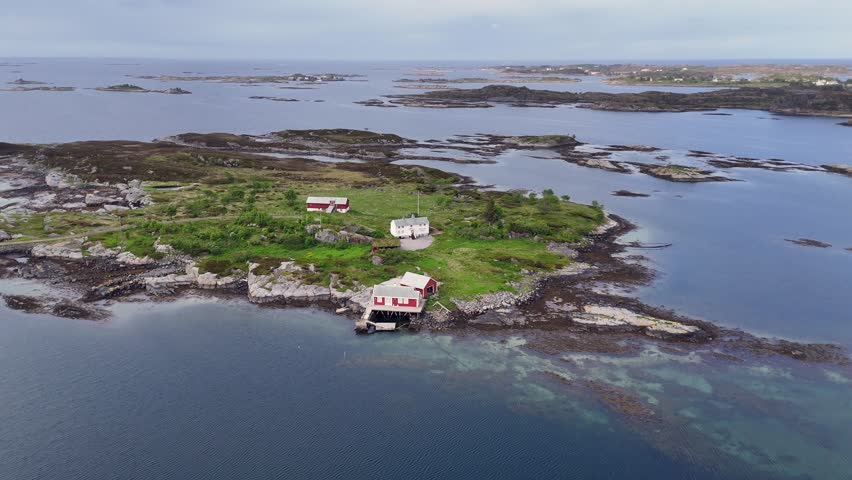 An aerial view capturing a peaceful farmstead perched on a small island beside Norway Atlantic Ocean Road, surrounded by sea and rugged coastline