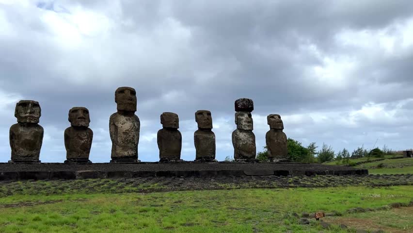 Daytime view of Ahu Tongariki on Easter Island, Chile. Fifteen iconic Moai statues standing against a bright blue sky with white clouds and the Pacific Ocean in the background. Famous archaeological site and UNESCO World Heritage destination.