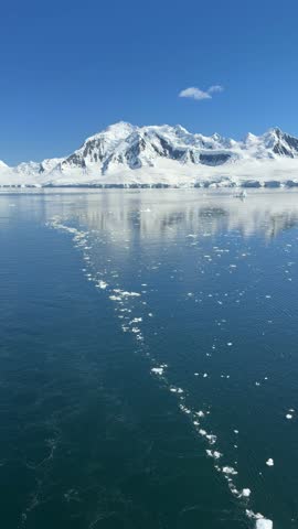 Beautiful Cruising in Antarctica. Move Backwards Across Line of Broken Icebergs. Feels Like Drone. Sunny Day White Snow Mountain (Vertical Video)
