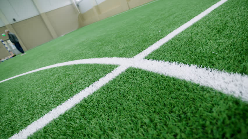 Indoor football field features artificial turf with crisp white painted lines. Prepared sports arena looks ready for competitive matches