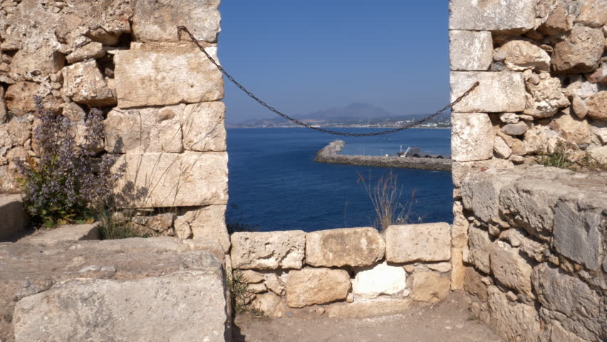 Panoramic Mediterranean sea view through ancient stone embrasure at Fortezza of Rethymno, Crete