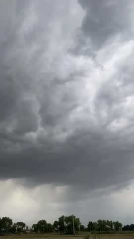 Dark storm clouds gathering over green countryside before heavy rainfall with dramatic monsoon weather and natural landscape.