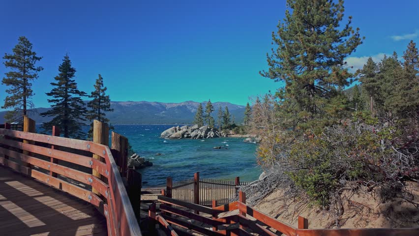 Scenic cove at Lake Tahoe with clear water, rocks, and mountain landscape in California. Natural lakeshore view with trees and beach access, ideal for travel and outdoor use