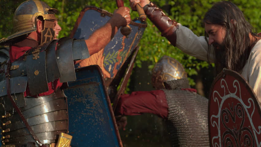 Close-up battle reenactment as Roman soldiers fight a Dacian warrior with shields and weapons outdoors.