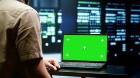 Computer scientist checks mainframes with a laptop mockup in a data center, keeping the green screen display ready for screen replacement and post production during green screen laptop. - Powered by Shutterstock - Get 15% off with code: PIKWIZARD15