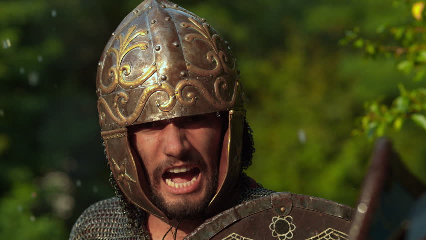 Close-up of armored Dacian warrior yelling during combat reenactment outdoors.