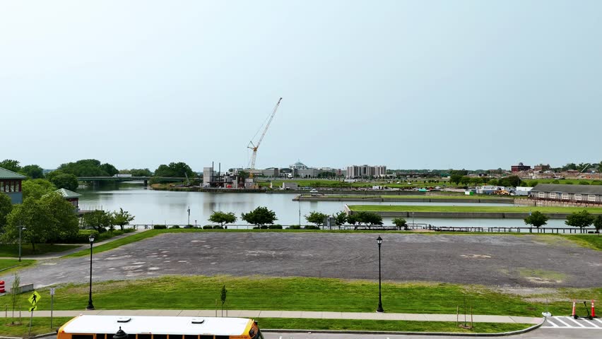 Construction of a museum along the shores of a lake and an inner harbor as activity of a city proceeds around it.