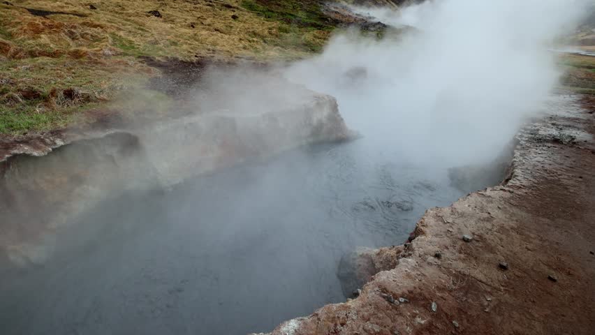 Geothermal mud pot boiling and emitting steam under overcast skies in Seltun Geothermal Area Krysuvik Reykjanes Peninsula Iceland
