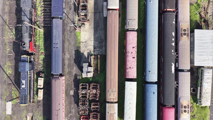 Old, colorful passenger trains and wagons stationary on multiple railway tracks in a train depot