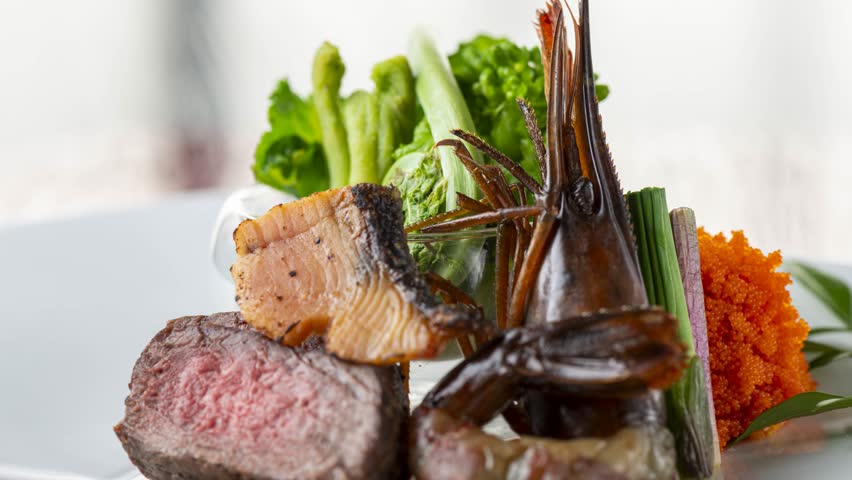Premium seared steak and shrimp artfully plated with fresh greens and roe on elegant white plate
