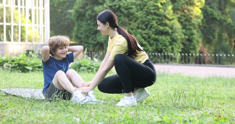 Mother helping her son to do exercise in park