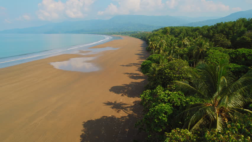 Pristine coastline and tropical jungle at wide empty sand beach in Costa Rica