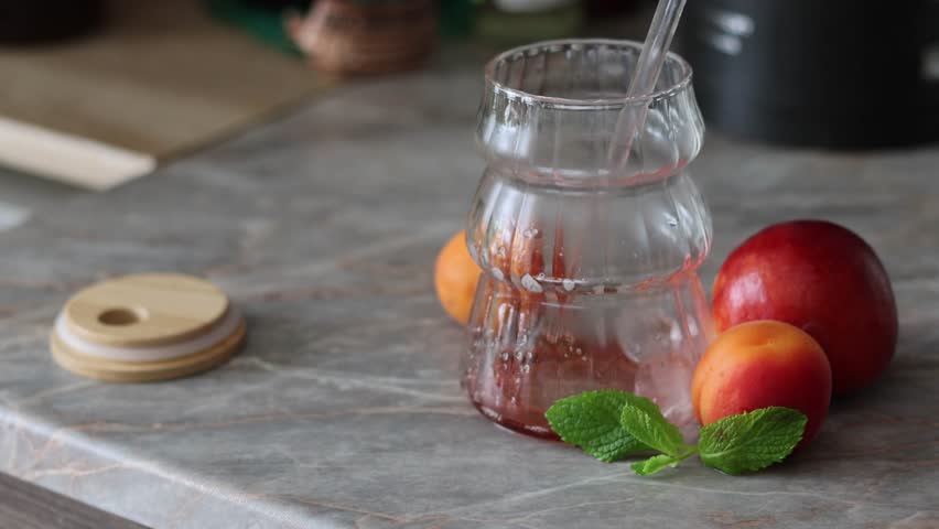 Pouring Red Juice or Wine into a Glass with Fresh Peaches and Mint
