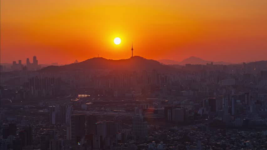 Seoul-South Korea. Golden sunset behind Namsan Tower overlooking the Seoul skyline, capturing the city’s tranquil evening atmosphere and vibrant urban landscape.Time Lapse Zoom in.