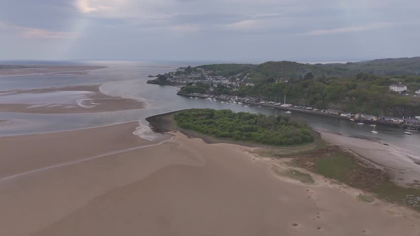 A scenic drone view of a shoreline city in Porthmadog in Wales, with sandy shores in the summer season, with plants in the background