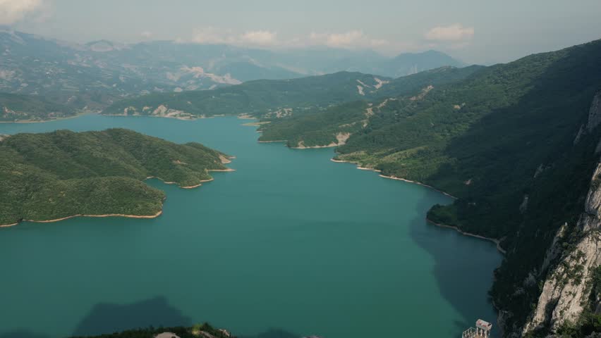 An  aerial landscape view of Lake Boville winds through lush mountain valleys under a hazy sky
