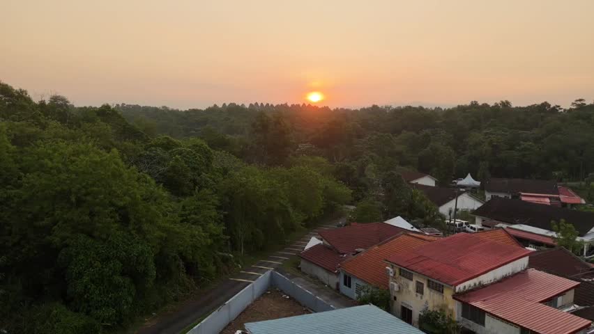 Beautiful 4K drone footage capturing a golden sunset over the lush green residential neighborhood of Skudai, Johor Bahru, Johor, Malaysia. Peaceful suburban landscape with trees, houses, and warm evening light.