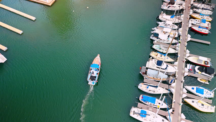 Motor boat with two men on board moves by waterscape. Rows of yachts stand at the berth. Waikiki, Hawaii, USA.