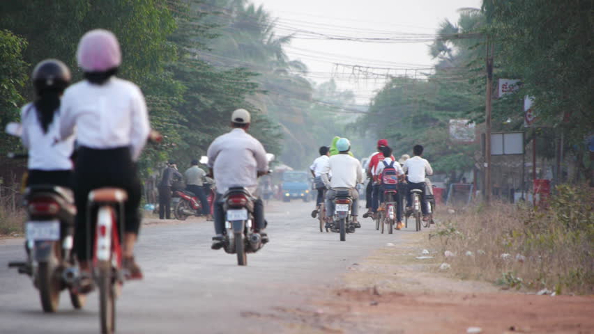 People riding motorcycles and bicycles in early morning Cambodia