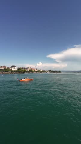 Peaceful view of Lake Zurich with clear water, boats and the surrounding urban landscape under sunny summer weather. Ideal footage of a popular European waterfront destination.