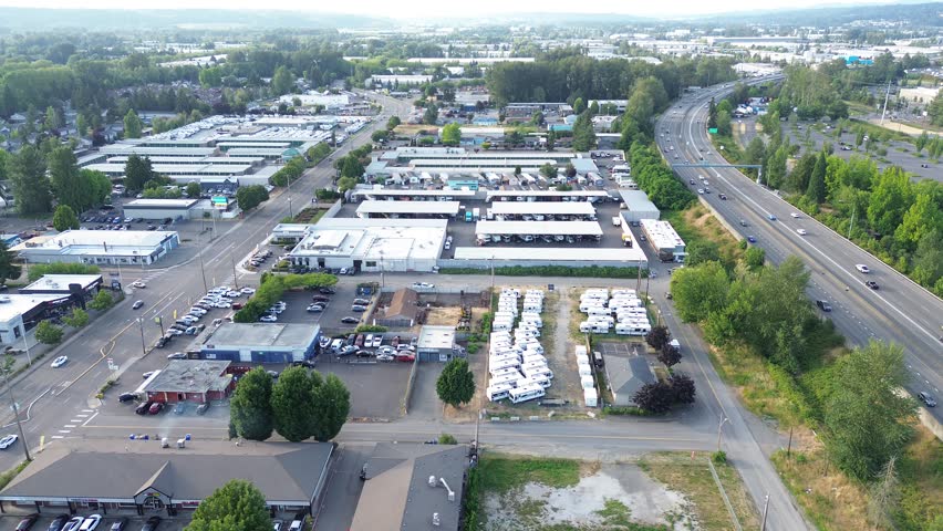 Kent valley arteries interstate 167 serves as primary industrial link near downtown district. Concrete highway spans above cluttered storage lots, while afternoon sun illuminates rooftops, WA. USA