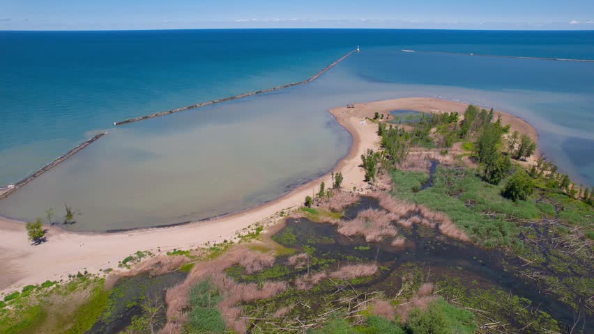 Drone footage revealing the sandy beach, breakwater, and marina at Presque Isle State Park.