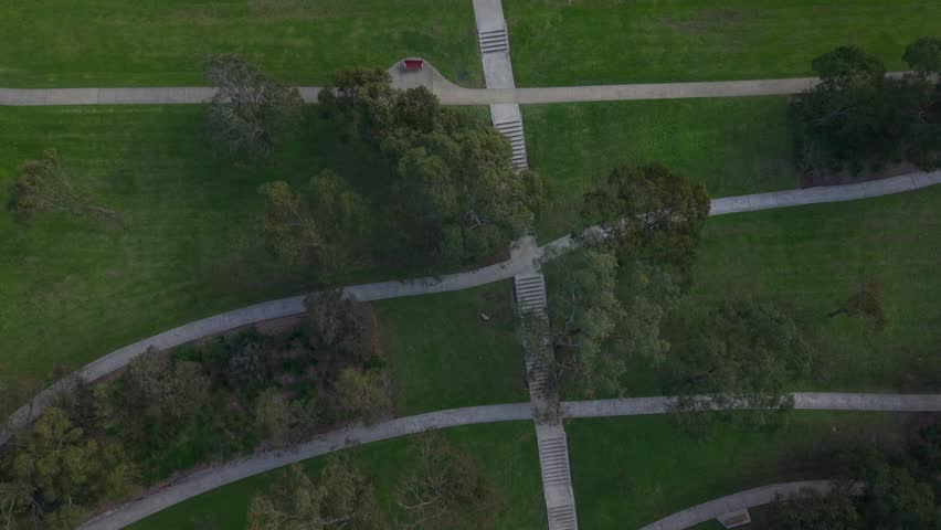 Aerial top-down view following a winding concrete path in a public park
