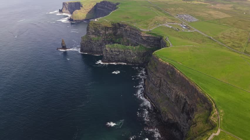 Aerial view of dramatic sea cliffs and green fields along the Atlantic coast in Ireland