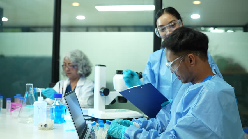 Life scientists researching in laboratory. Focused female life science professional pipetting solution into the glass cuvette. Healthcare and biotechnology concept.