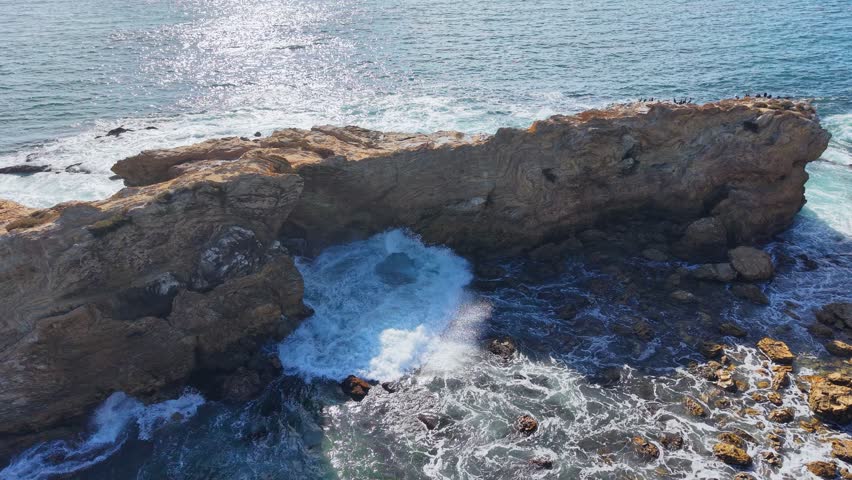 Pacific ocean waves crashing on rocky California coastline.